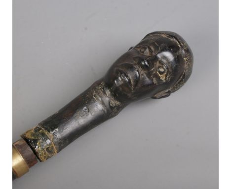 An early 20th century African tribal sword stick with carved bust pommel. Length 94cm. CANNOT POST OVERSEAS.  