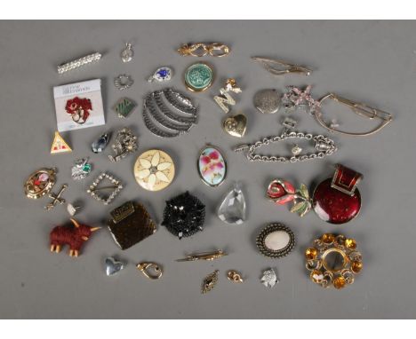 A collection of costume jewellery brooches, pendants and scarf clips to include highland cow, cameo and floral examples.  