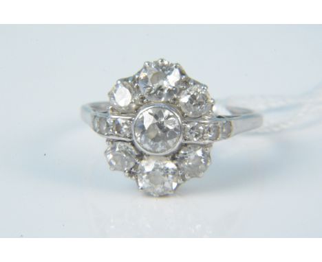 A platinum diamond cluster ring, the centre old cut collet set stone flanked by a row of three small old cut stones terminati