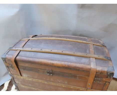 A travelling trunk, domed top with wood and metal bracings and leather straps and handles AF. Initials â€œMNâ€ stamped on the
