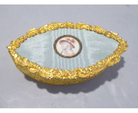 A late 19th century cast gilt trinket box of ovoid form, the lid covered with watered silk and an enamel miniature of a noble