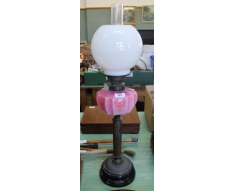 A brass column oil lamp with pink glass bowl