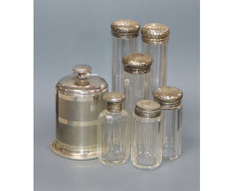 A George V engine turned silver cigarette dispenser, Birmingham, 1935 and six silver lidded glass toilet jars.