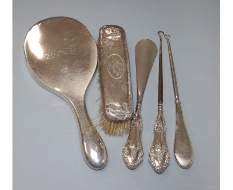 A silver backed mirror, a brush, a shoe horn and two button hooks.