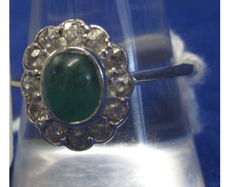 CABOCHON EMERALD AND DIAMOND CLUSTER RING. The oval cabochon cut emerald and estimated 8 x 6.5mm in collet setting surrounded