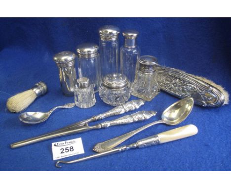 A collection of silver topped dressing table jars, silver caddy spoon, silver handled glove stretchers etc. (B.P. 24% incl. V