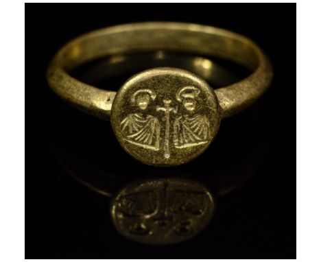 Ca.600-800 AD. A gold round section hoop with attached round bezel; the bezel engraved with two nimbate saints around a centr