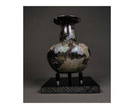 Ca.400 AD. A Roman glass flask with a discoid body, tapering in profile, tubular neck,wife flared mouth; iridescent surface. 