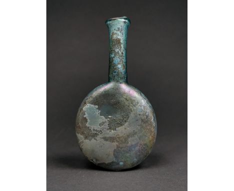 Ca.200-300 AD. A light blue glass flask with a discoid body, tapering in profile, tubular neck, iridescent surface. Fine Cond