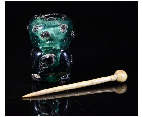 Ca.400 AD. An amazing Roman cosmetic set formed by a square-shaped green glass flask with an applied black dot and a bone app