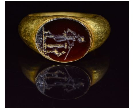 Ca.200 AD. A hollow gold ring with D-section hoop and elliptical bezel containing a finely cut red hardstone intaglio depicti