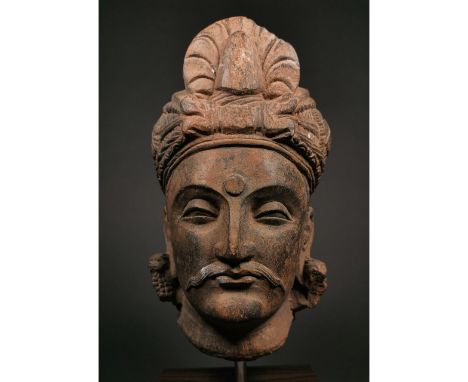 Ca.300 AD. A life-size schist head of a bodhisattva with a round face and fleshy features, heavy-lidded eyes, long earlobes w