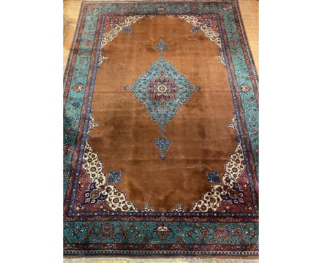 A large North West Persian carpet, hand knotted, the field of blues, browns and reds with scrolling arabesques within a turqu