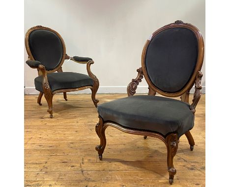 A pair of mid Victorian His and Hers walnut framed easy chairs, the oval back with floral carved crest, upholstered in grey v