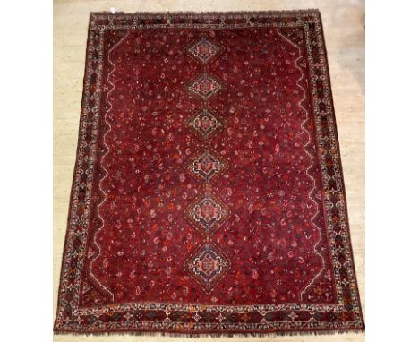 A Shiraz hand knotted carpet, the red field with pole medallion and intricately decorated with stylised camels, birds and flo