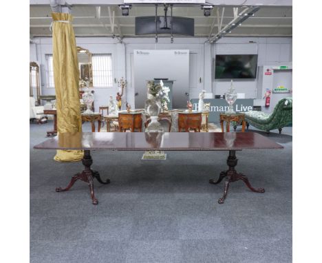 AN 18TH CENTURY STYLE MAHOGANY TWIN PILLAR EXTENDING DINING TABLEWith gadrooned border, on dual carved tripod supports, resti