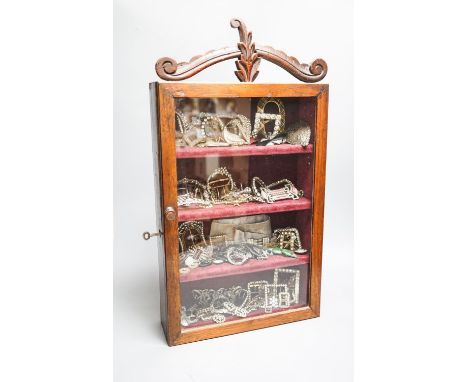 A large collection of 19th/20th century paste and enamel belt and shoe buckles and clips, contained in an oak display cabinet