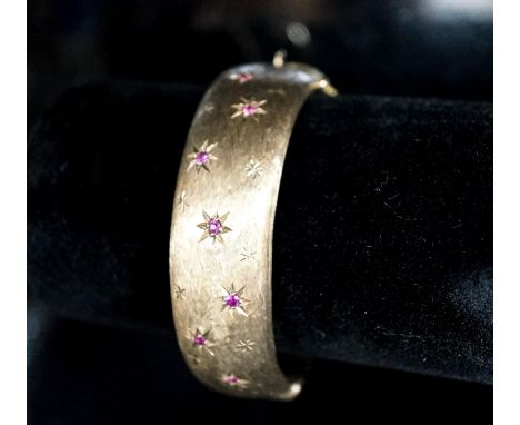 A 1960's engraved 9ct gold and ruby set hinged bracelet, interior diameter 58mm, gross weight 35.7 grams.