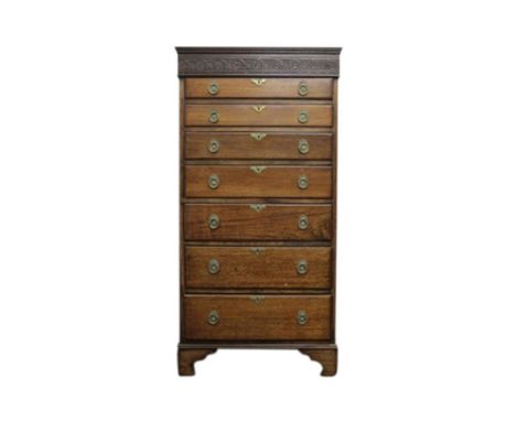of rectangular form, the carved top resting on seven graduated drawers with brass ring handles, all raised on bracket feet, 8