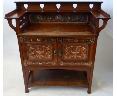 An Arts & Crafts side cabinet With galleried top section and double doors over a base shelf, applied with floral copper panel