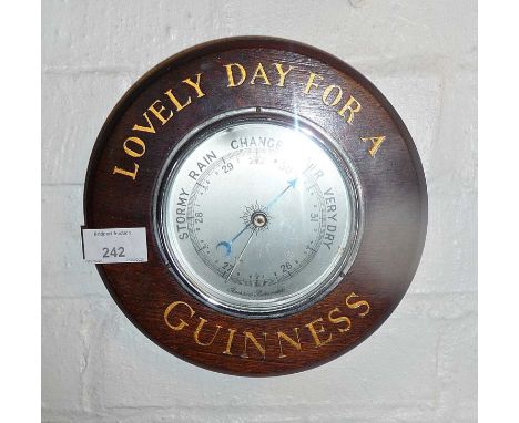 Old advertising aneroid barometer mounted on round oak base inscribed "Lovely Day For a Guinness"