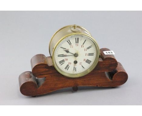 Brass Circular Clock, the white enamel dial with black Roman numerals and red Arabic numerals fitted on a wooden stand