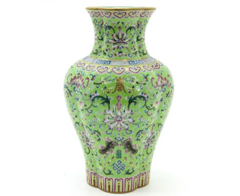 Light green ground with Famille Rose enamels depicting florals and Chinese symbols in gold gilt, marked Jiajing, 23 cm. tall.