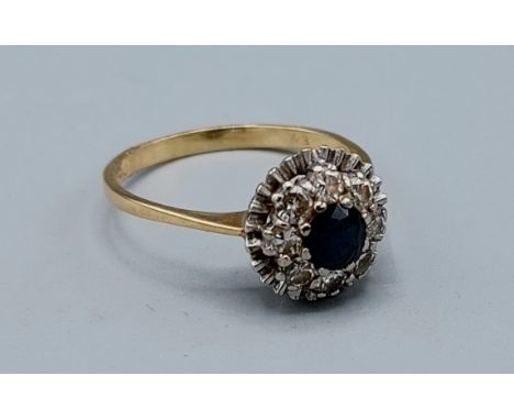 An 18ct gold Sapphire and Diamond cluster ring set with a central Sapphire surrounded by Diamonds, 3.9gms, ring size T 