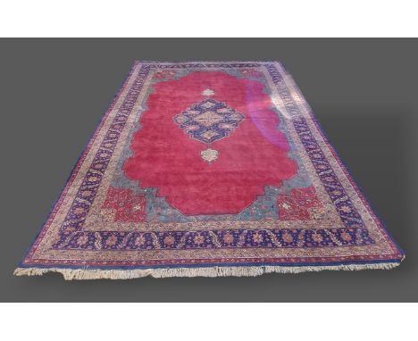 A North West Persian woollen carpet, with central medallion upon a red and blue ground within multiple borders, 336cm by 487c