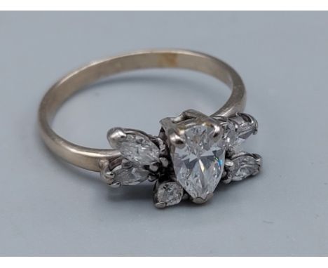 An 18ct white gold ring set with a central pear shaped Diamond flanked by other Diamonds, 3.3gms, ring size O 