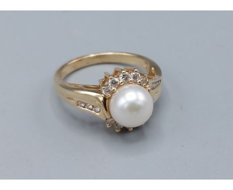 A 14ct gold ring set solitaire pearl surrounded by Diamonds with Diamond shoulders, 4.6gms, ring size N 