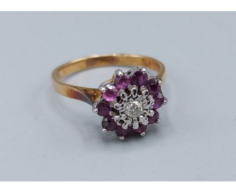 An 18ct gold Diamond and Ruby set cluster ring with a central Diamond surrounded by Rubies, claw set, 4.1gms, ring size R 