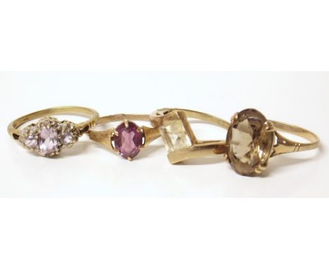 Four 9ct&nbsp; gold dress rings, one smokey quartz set, one three-stone amethyst, one set with purple paste, and one topaz se