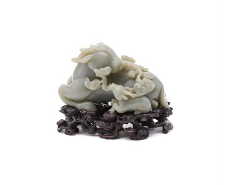 A Chinese celadon jade model of a deer, 19th or 20th century, the recumbent animal with its head turned back and holding a br