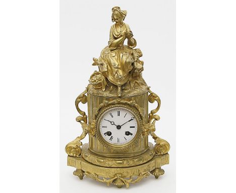 Tischpendule im Stil Louis XVI. Vergoldete Bronze. Sockelförmiges Gehäuse mit Rocaillen, Ranken und vollplastischem Mädchenau