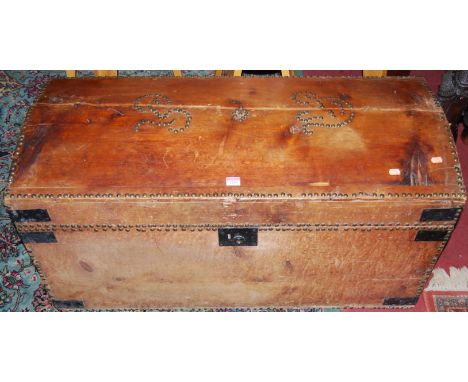 A 19th century stained pine, brass studded and further metal bound domed hinge top travelling trunk, having iron end carry ha