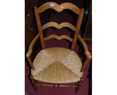 An early 20th century beech ladder back rush seat elbow chair, together with a further ladder back X-frame elbow chair (2)