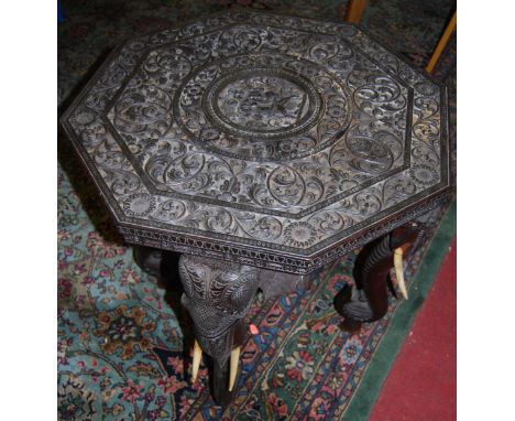 A circa 1900 Indian heavily carved hardwood octagonal occasional table, raised on elephant trunk supports with ivory tusks, d