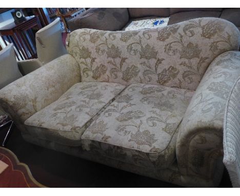 A contemporary two seater sofa with cream damask upholstery raised on block legs
