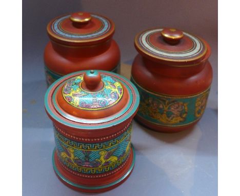 Two late 19th Terracotta tobacco jars and covers, decorated enamel with putto depicting amongst C-scrolls, together with anot
