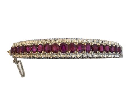 An 18ct gold ruby and diamond hinged bangle,  An 18ct gold ruby and diamond hinged bangle, the oval shape ruby line with sing