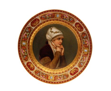 A late 19th Century Vienna cabinet plate decorated with a hand painted portrait of a young lady with her hands beneath her ch