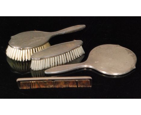 A hallmarked silver engine turned four piece dressing table set composed of two brushes, hand mirror and comb, Birmingham 195