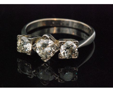 A platinum and diamond three stone diamond ring, central brilliant cut diamond claw set beside two further brilliant cut ston