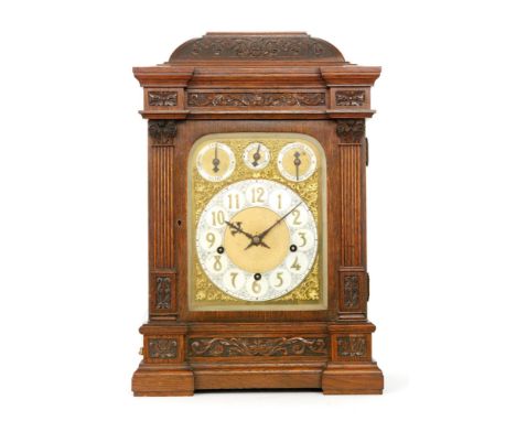 An early 20th Century oak cased bracket clock, with garland cornice, foliate carved frieze panels and pilaster columns to the