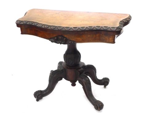 A Victorian figured mahogany card table, the serpentine shaped top with a carved edge, on a baluster shaped carved column and