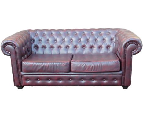 A red oxblood leatherette two seat Chesterfield sofa, 180cm wide.