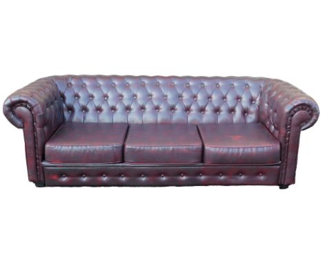 A red oxblood leatherette three seater Chesterfield sofa, 221cm wide.