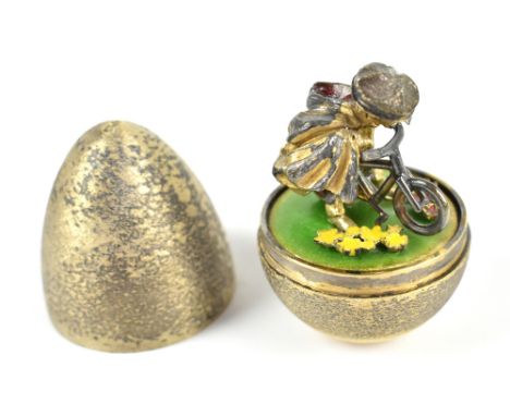 STUART DEVLIN; a limited edition silver gilt surprise egg, the cover enclosing a gilt and enamelled figure riding a bicycle, 