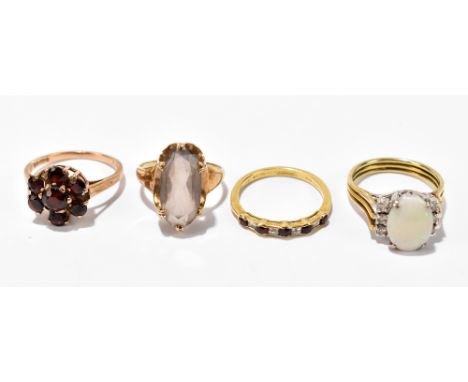 Four 9ct yellow gold dress rings comprising an opal example, size N, a smoky quartz example, size K, garnet example, size O a